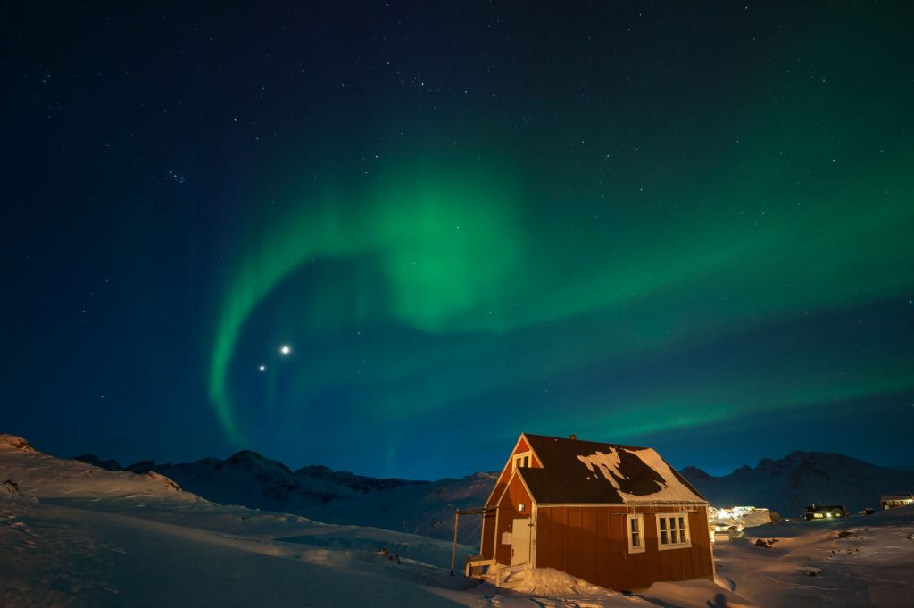 a small house underneath the northern lights in the sky