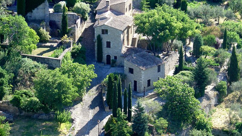 The ancient buildings of a small village in Provence with lots of greenery.