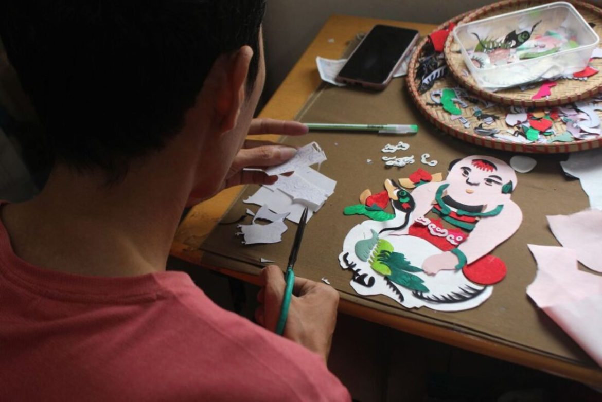 a man cutting silks with scissors for a craft he is creating