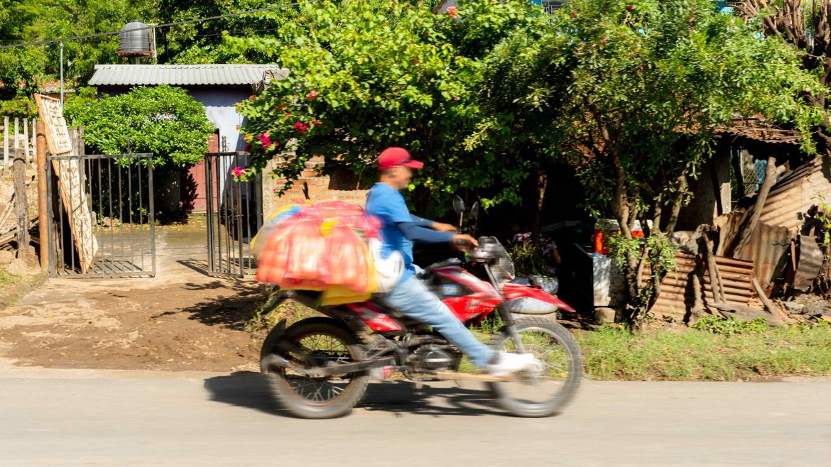 A person in a blue shirt driving a motorbike through the street in Nicaragua