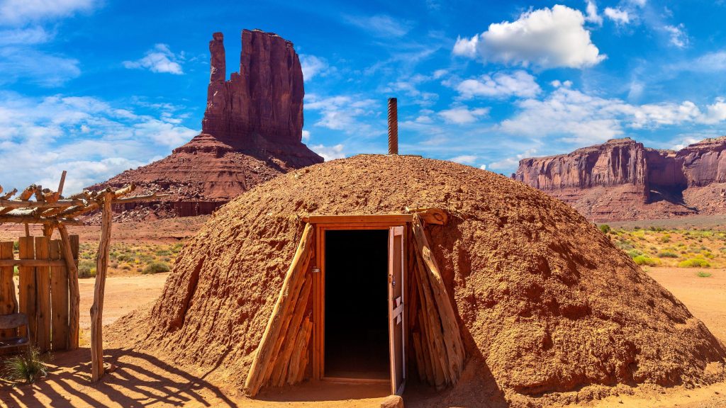 A sand cave in Utah with massive sandstone monuments in the back. 