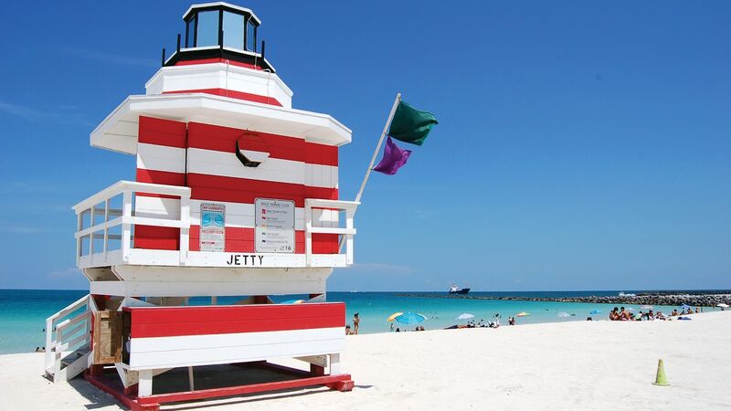 A multicoloured lifeguard tower, sitting on pure, white sand on a beach in Miami