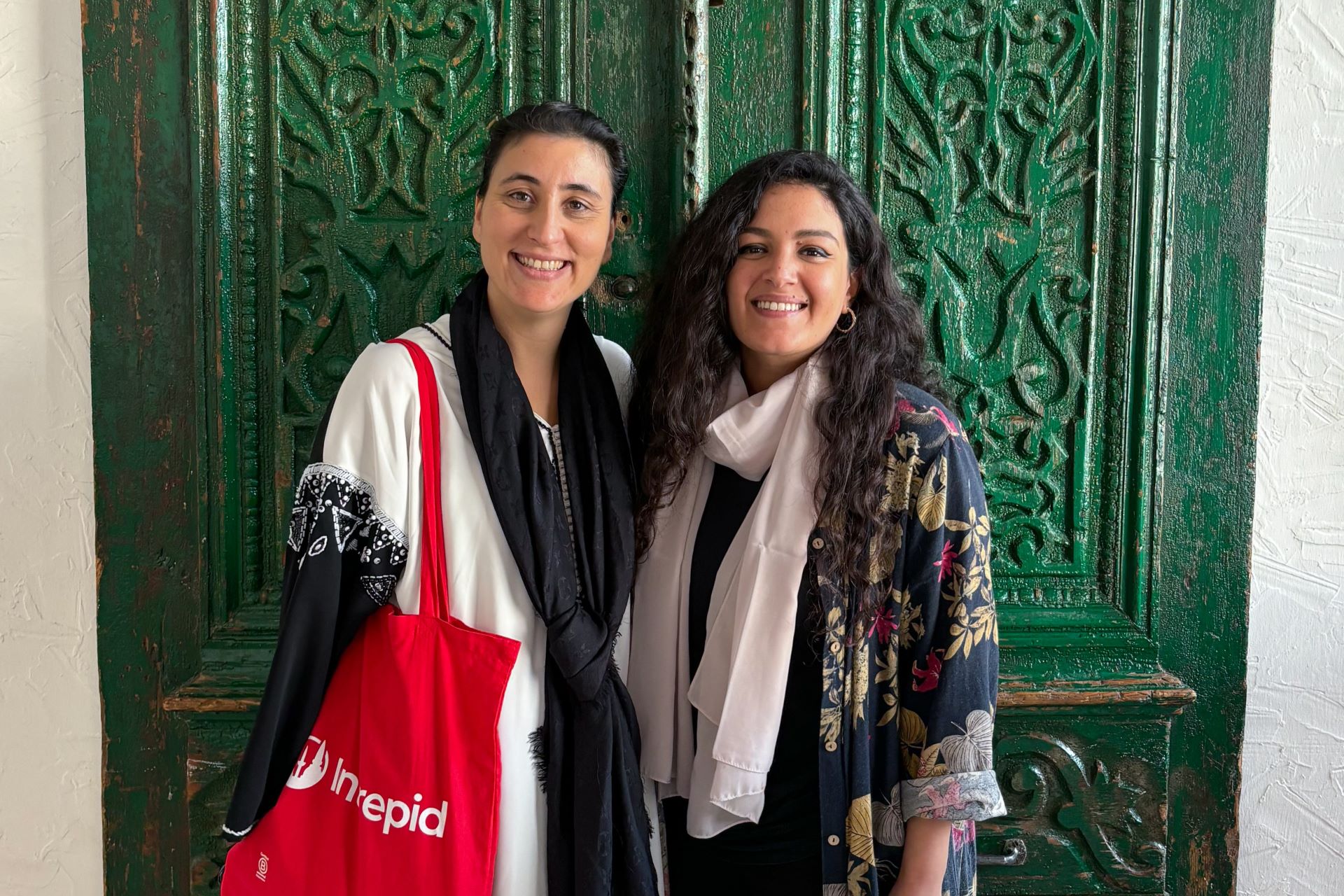 two women standing in front of a green door