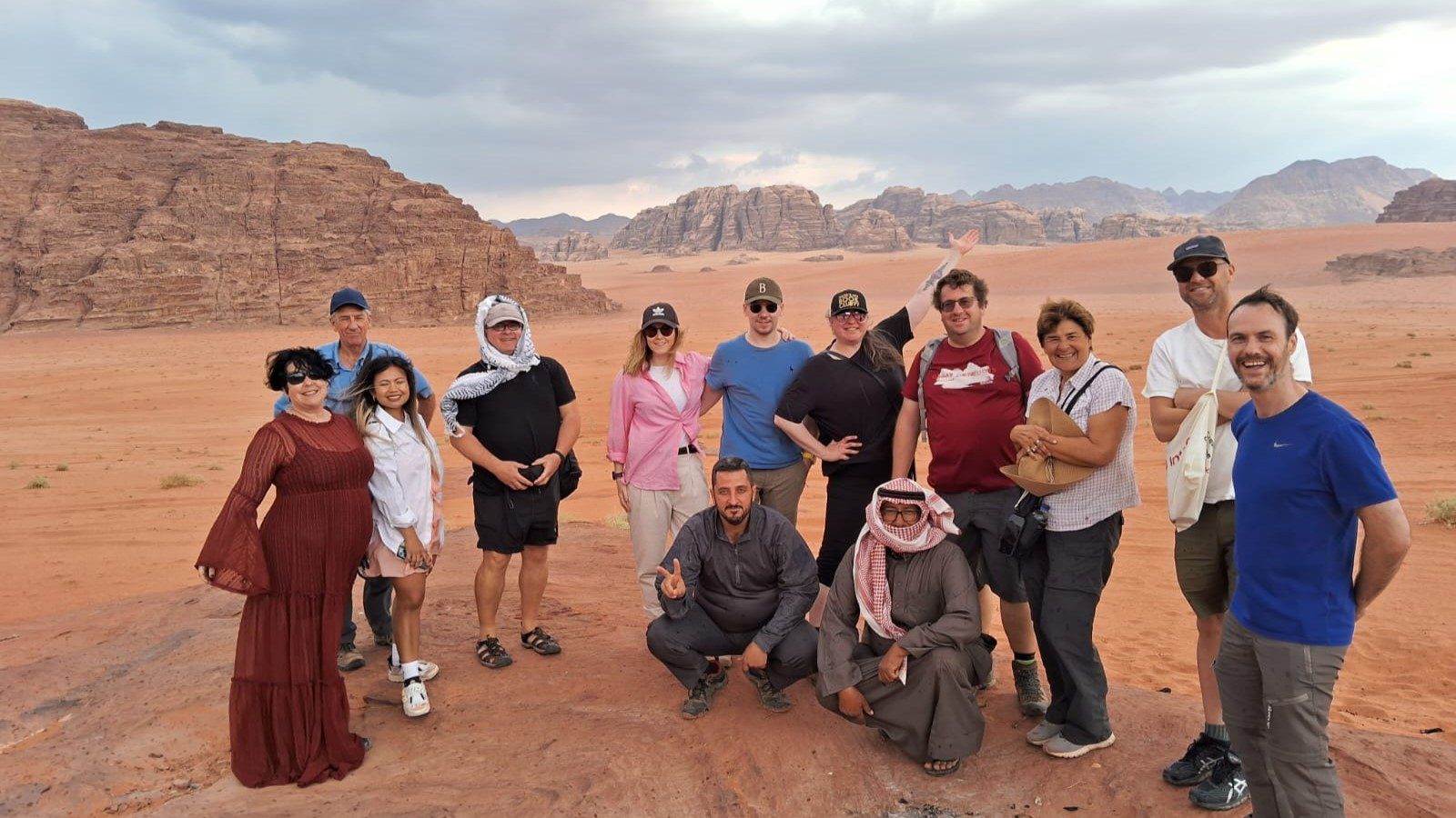 a group of travellers smiling for a photo in wadi rum