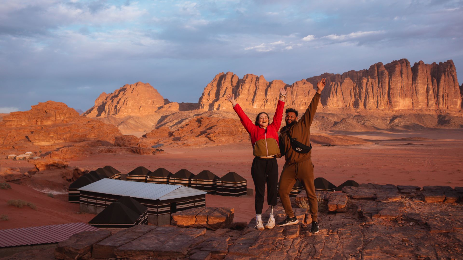 a man and a woman in the wadi rum with their arms in the air