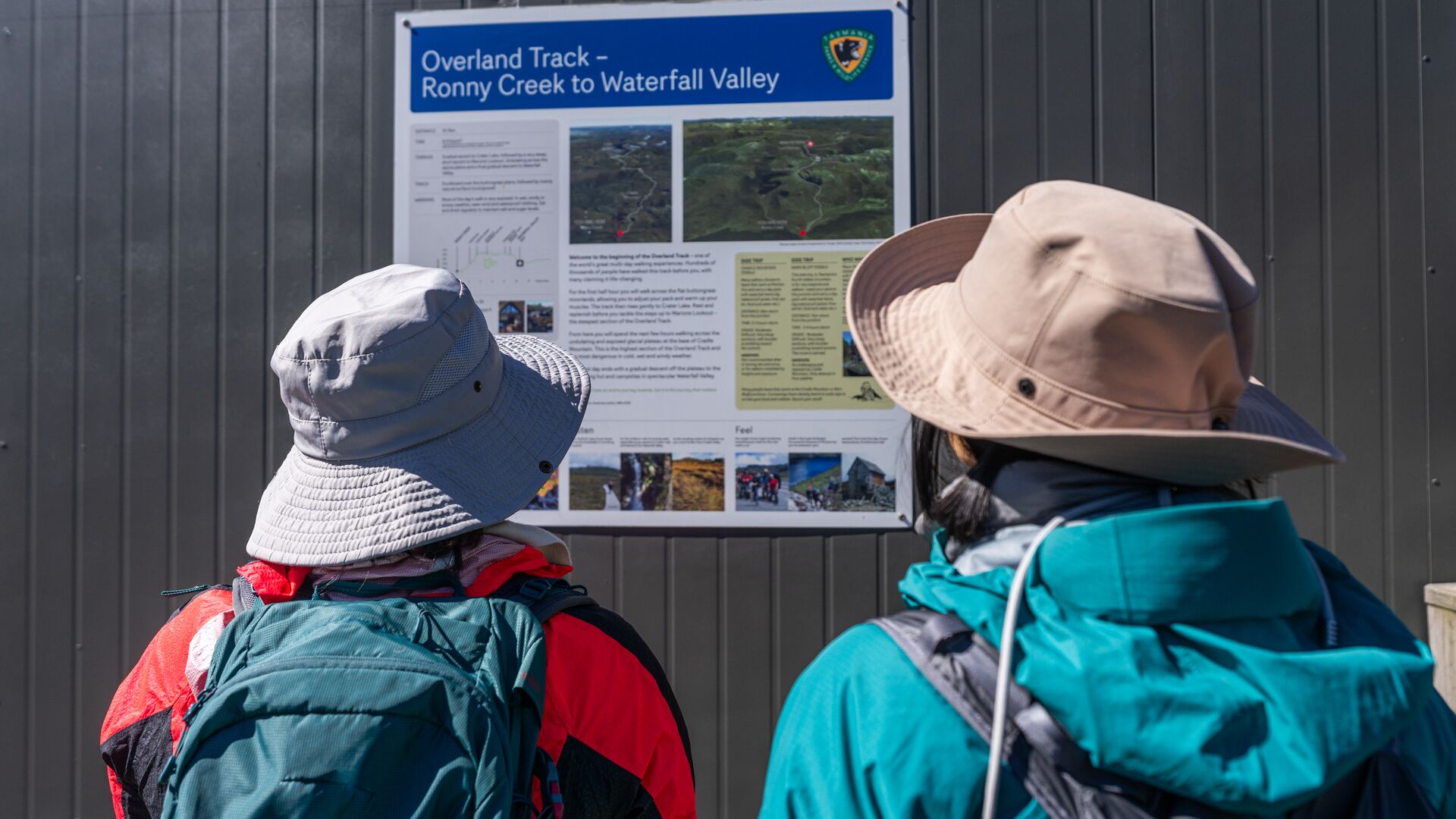 Two people look at an information sign for the Overland Track.