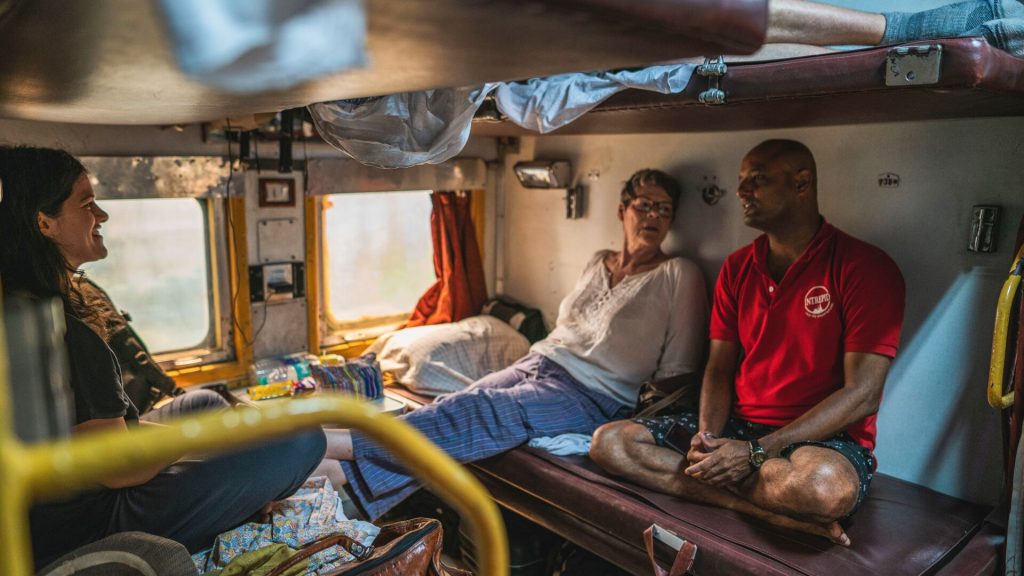 Two travellers and and Intrepid leader chatting on a sleeper train in India