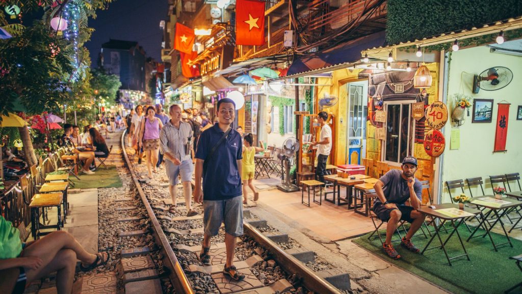 A group of travellers walking along train tracks in Hanoi, Vietnam
