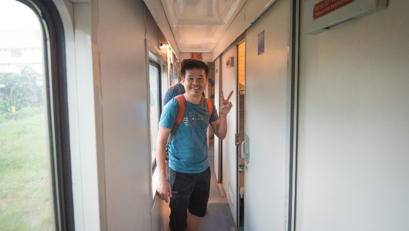A traveller gives a peace sign in the hallway of a train.