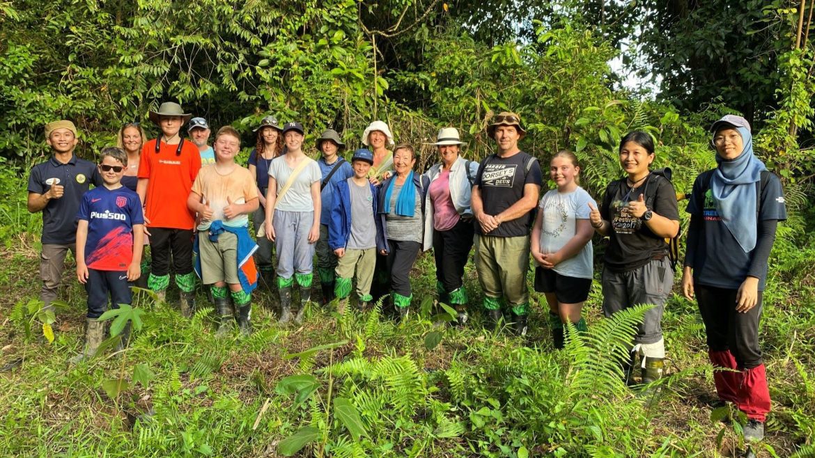 a group of people standing in the borneo forest