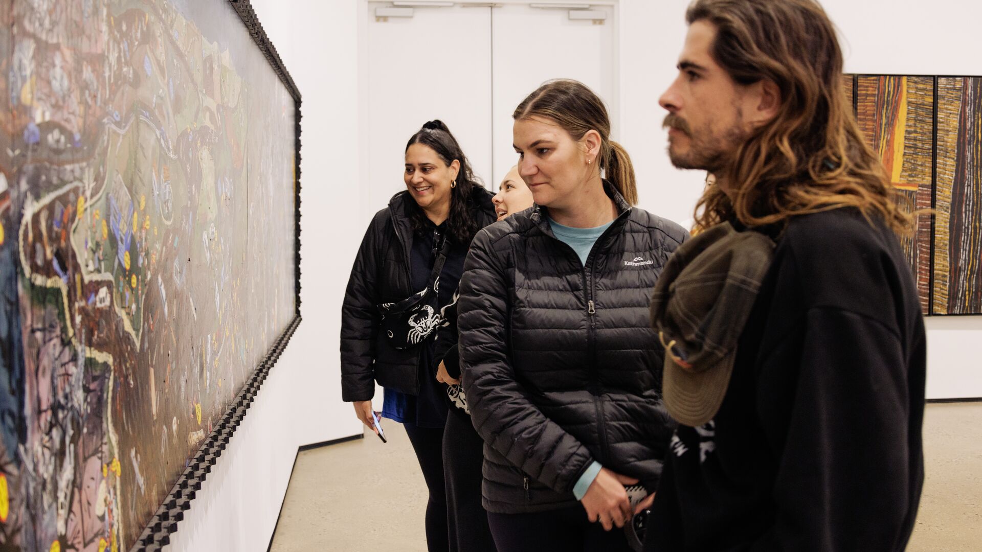 A group of people look at a painting in a Victorian gallery.