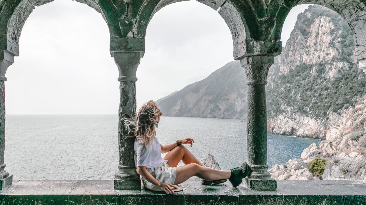 a woman sitting by marble pillars looking at the view in Porto, Italy