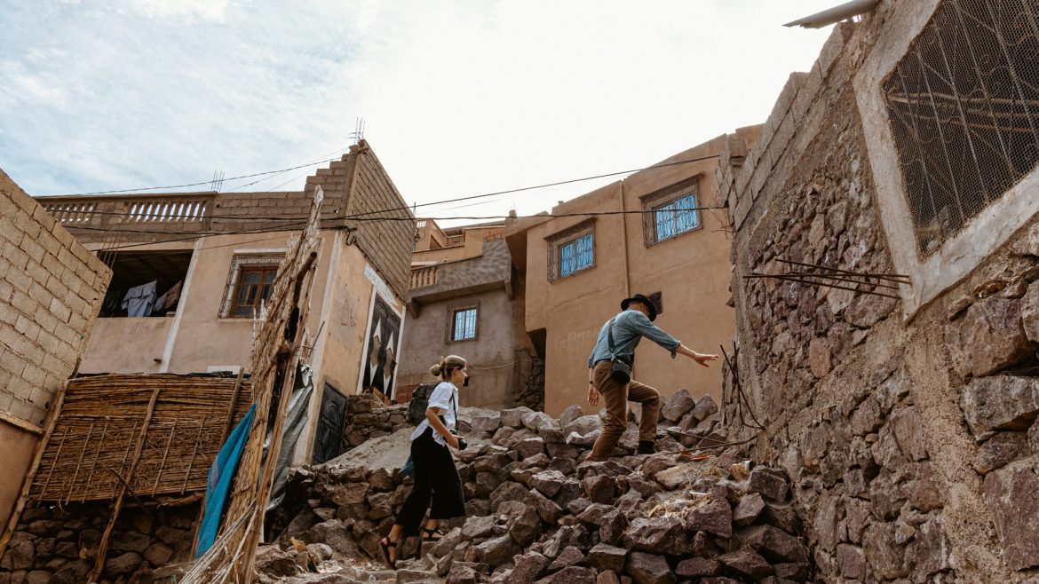 Two travellers climb over rubble in Morocco post-earthquake