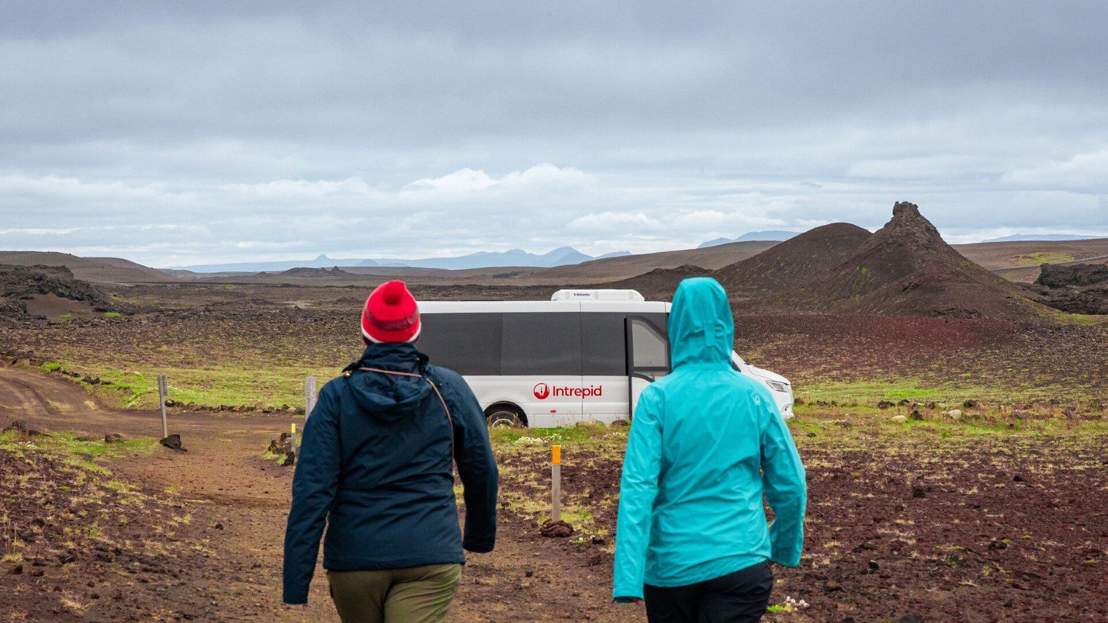 Two travellers walk towards an Intrepid minivan in Iceland