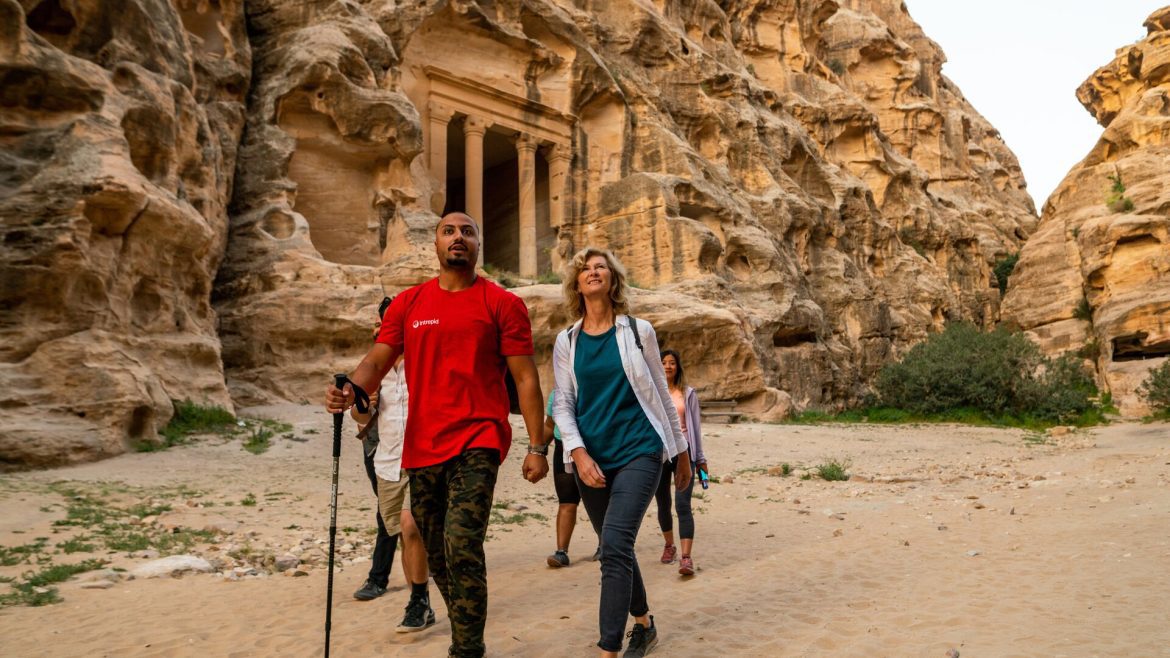 An Intrepid leader in his classic red tee, leading travellers through Petra, Jordan