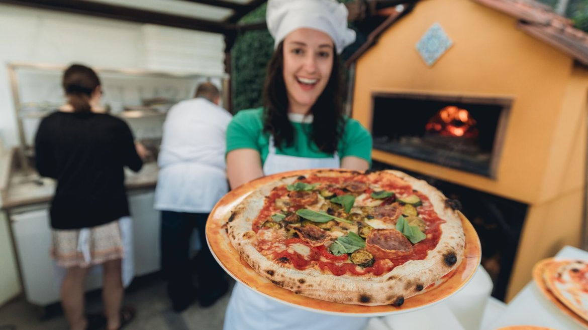Traveller in a chef's hat showing off the pizza she just made in Sorrento, Italy