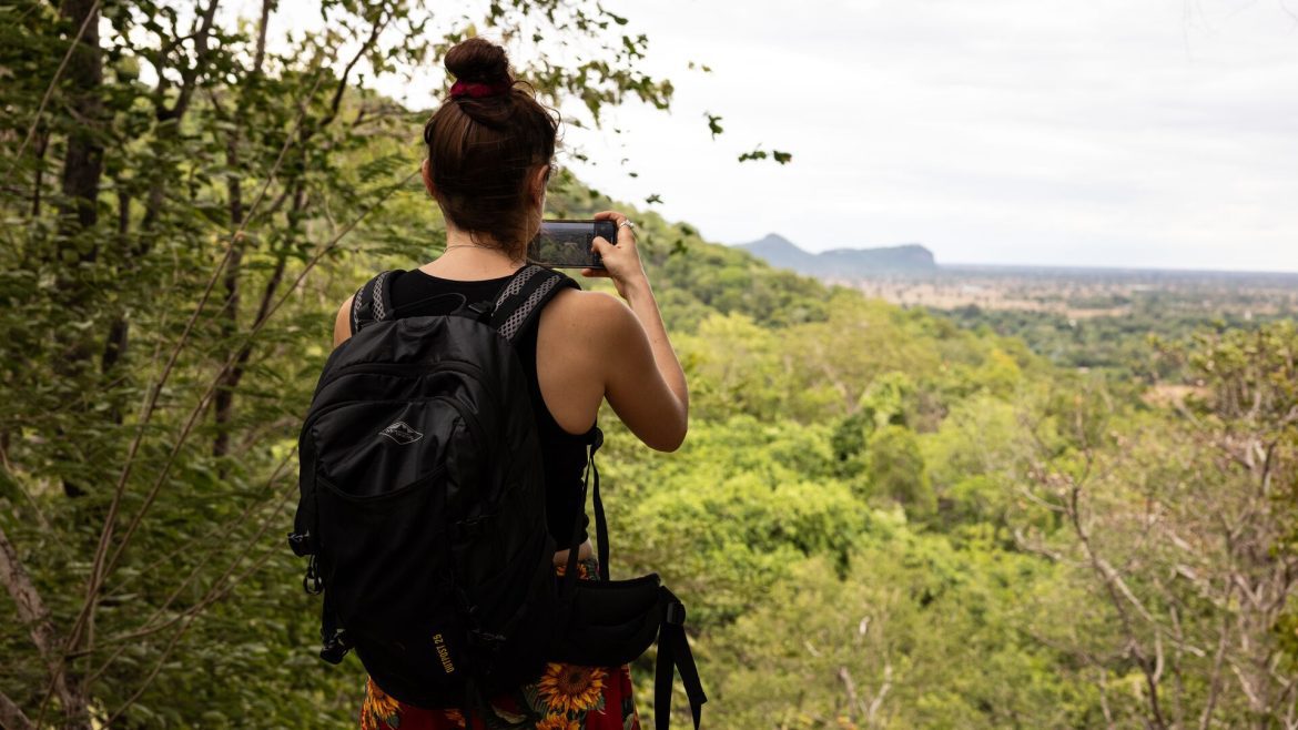 Woman hiking in Cambodia pauses to take a photo on her smartphone