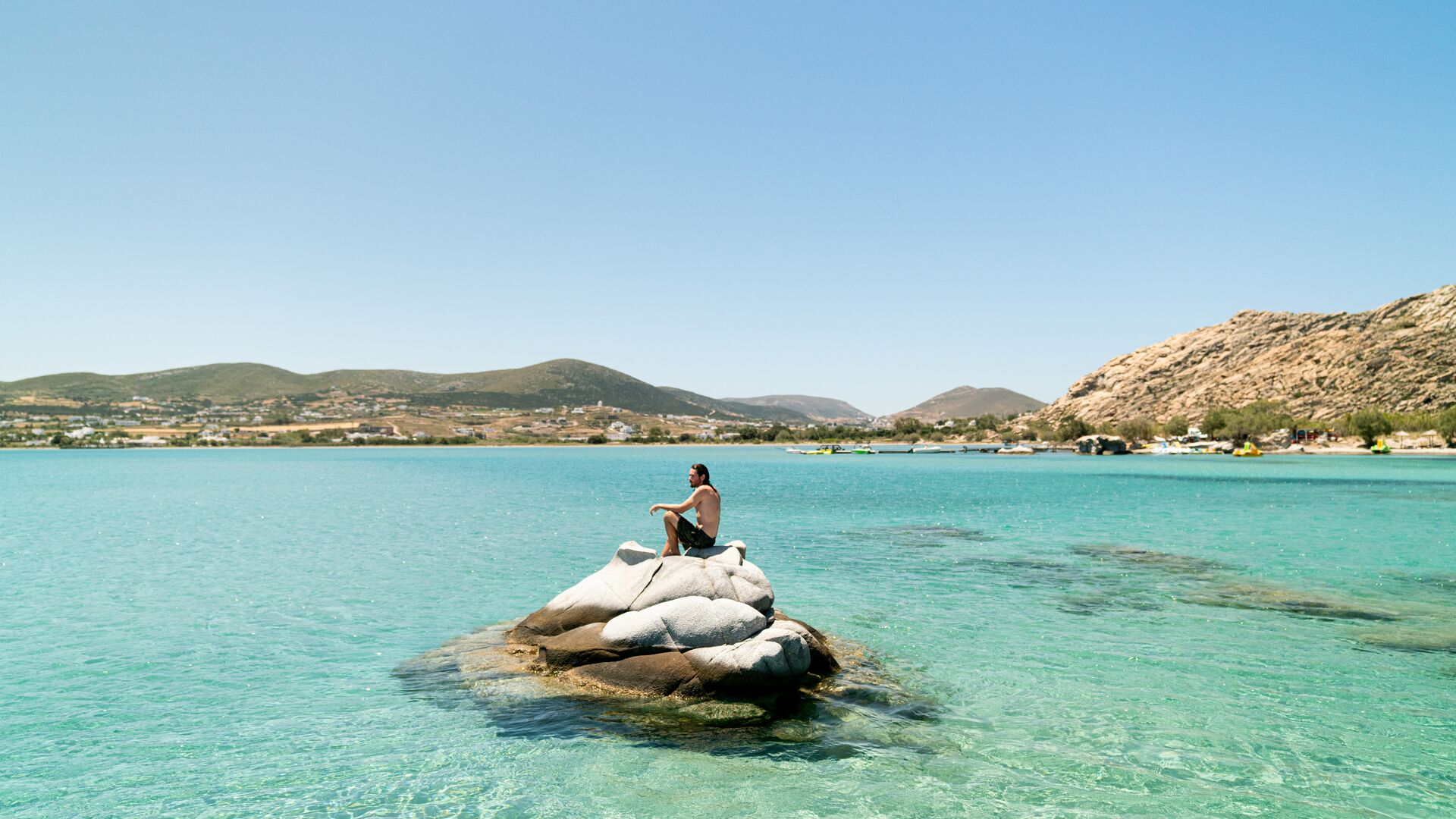 A man relaxing amid clear water on a Greek island.