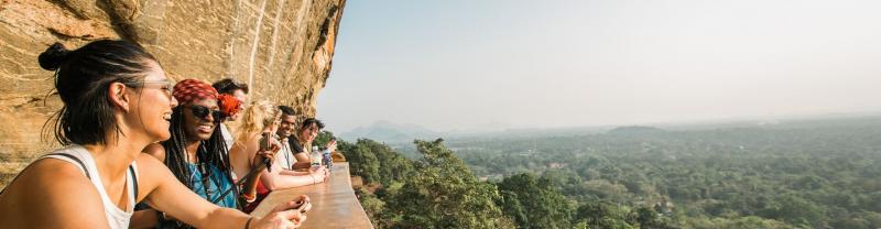 group of people looking out at green forest from lion rock fortress in Sri Lanka
