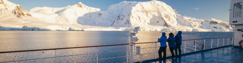 Passengers on board ship in Antarctica look at view from balcony 