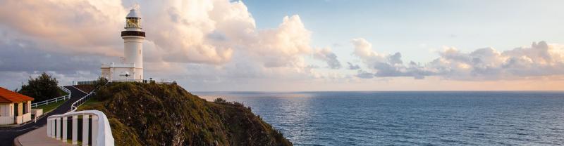The Cape Byron Bay lighthouse at sunset with the ocean in the background. 