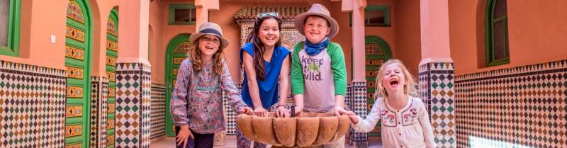 A group of four kiddos smiles and poses on a family trip in Morocco