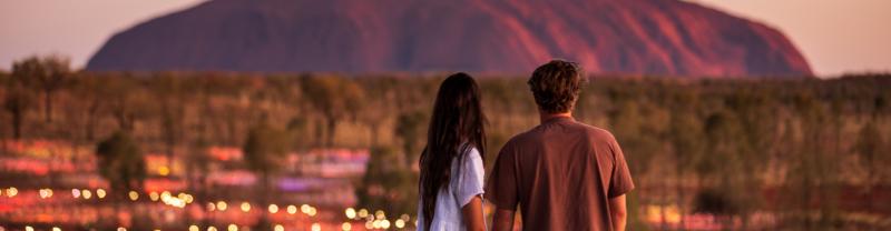 A couple looking out over Uluru at sunset. 