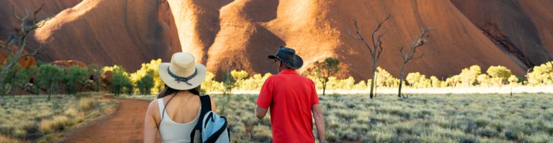 An Intrepid tour leader and a traveller walking towards the base of Uluru on the Mala Walk