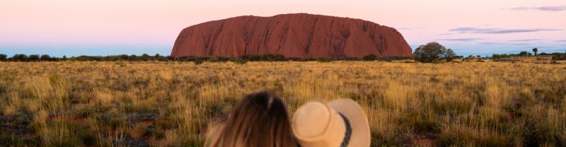 Two travellers admiring the view of Uluru at sunset