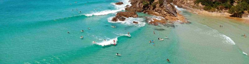A cluster of surfers takes turns on the waves in Byron Bay