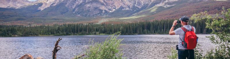 A traveler taking a photo of a mountain in Jasper, Canada