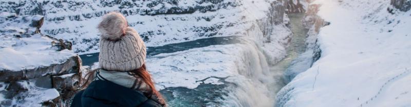 A traveller admiring the view of a frozen Gullfoss Waterfall in Iceland
