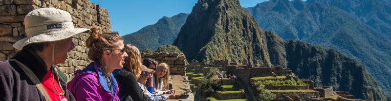 A group of travelers overlooking the ancient ruins of Machu Picchu on a clear, sunny day.