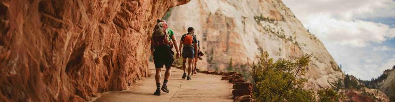 Hikers walk under a rock formation in Utah's Zion National Park