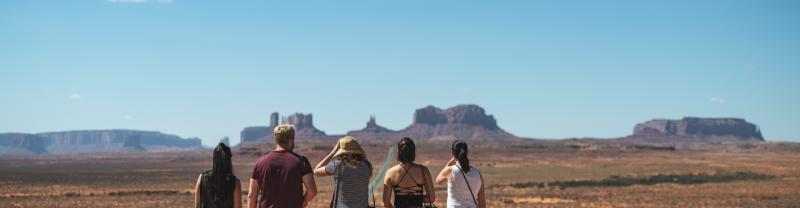 A group of travelers standing in Monument Valley under a blue sky in Arizona 