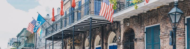 A balcony with the United States flag flying on Bourbon Street. 