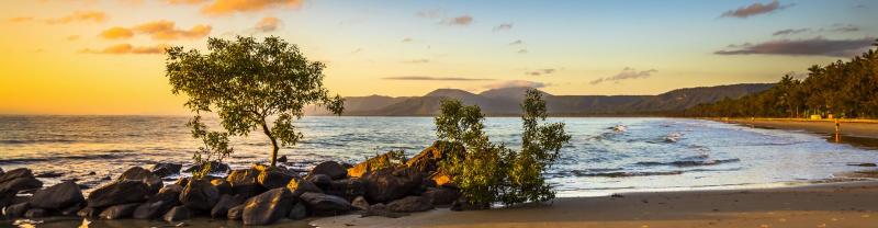 The rocky shoreline of a beach in Port Douglas at sunset 