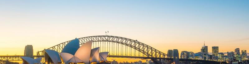 The sun sets over the Sydney Opera House and the Sydney Harbour Bridge