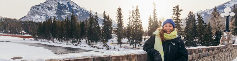 A woman smiling at the camera in front of a snowy landscape in Banff National Park, Canada.