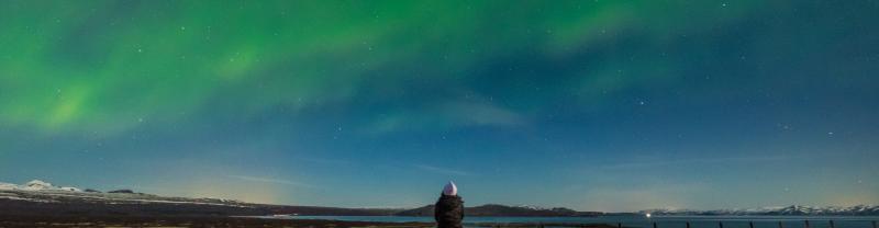 A lone traveler staring up at the Northern Lights in Iceland