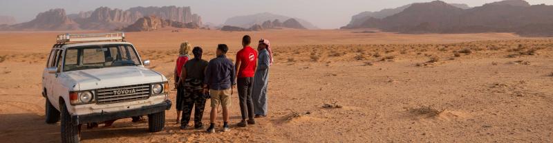 Travelers gather by an off-road vehicle in Wadi Rum, Jordan