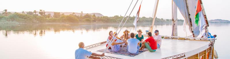 Intrepid travellers and leader crusing down the Nile on a felucca at sunset