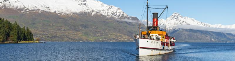 boat cruising on a lake with a snowy mountain in the background