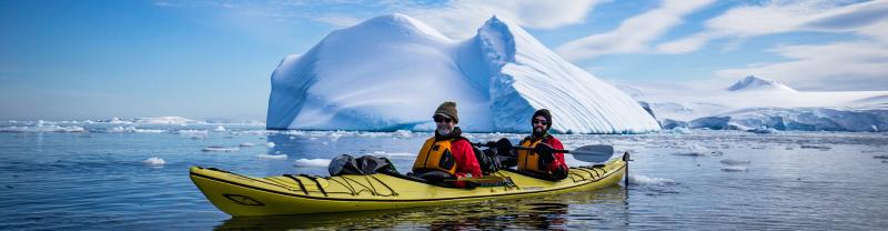 A pair of kayakers exploring Antarctic icebergs