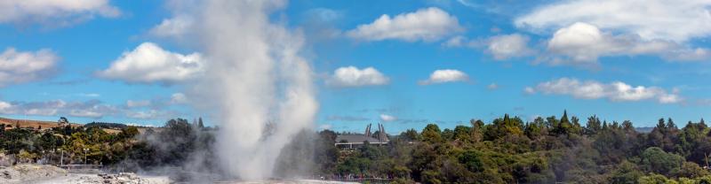 Geyser erupting with steam in front of the blue sky