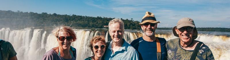 Smiling travelers standing in front of Iguazu Falls
