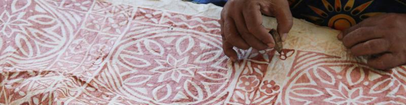 A Samoan women drawing a traditional pattern on a banner