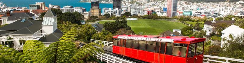 Wellington red cable car climbing the hillside with a view over the city