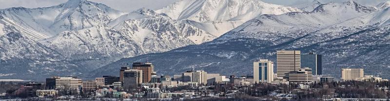 The Anchorage skyline in front of snow-topped mountains 