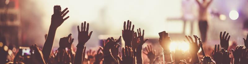 People waving their hands in the air at a festival 